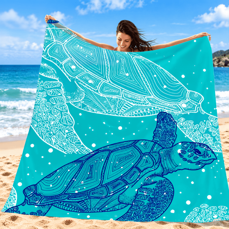 Portable Beach Mat – Sandproof Waterproof Camping & Picnic Blanket A woman on a sandy beach holds up a large turquoise towel or blanket featuring two white and blue sea turtle designs with intricate mandala-style line art.