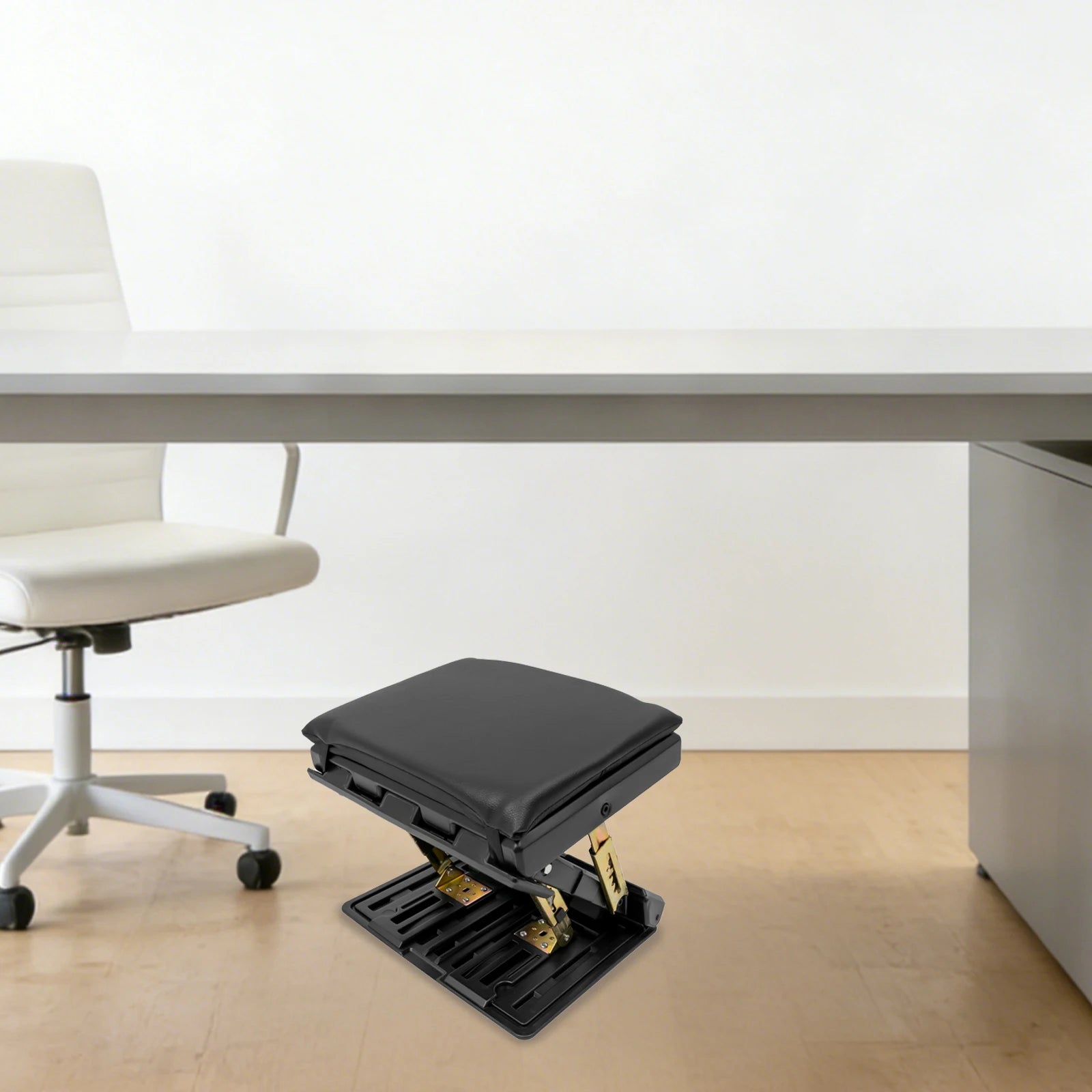 Adjustable Foldable Footrest – Ergonomic Footrest for Car, Office & Home A black office footrest with gold-toned metal supports, positioned under a light gray desk in a minimalist office setting with a white chair and light wood floor.