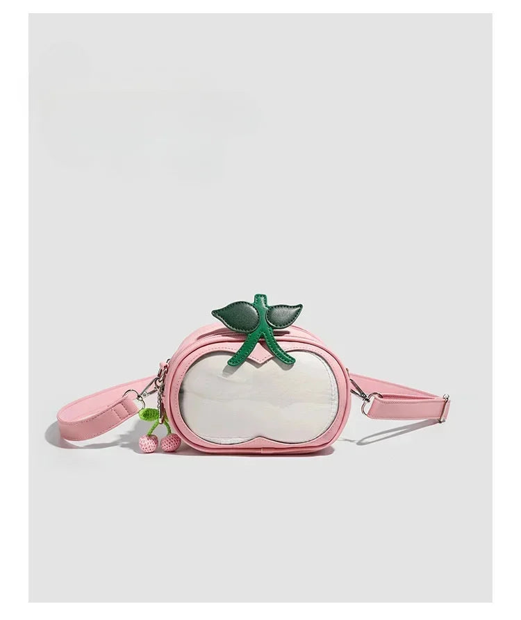 Apple-Shaped Crossbody Phone Purse – Lightweight Shoulder Bag A pink faux-leather waist bag designed to look like a peach, featuring a clear front window, a green leaf and stem accent on top, and a pink cherry charm, shown against a light gray background.
