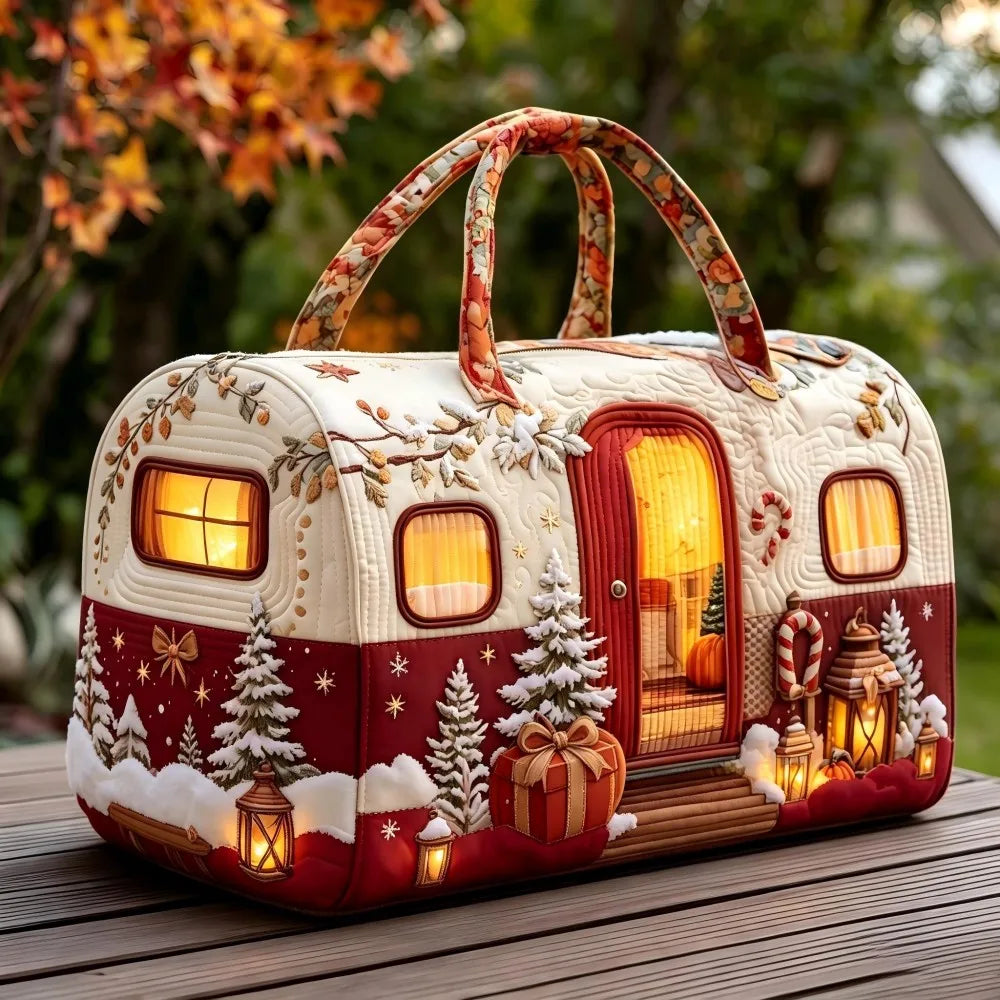 Christmas Quilted Travel Tote Bag – Vintage Camping Car Handbag A decorative camping trailer-shaped handbag with a winter holiday theme, featuring a cream and red design with snowy trees, glowing lanterns, and warm window lights, set on a wooden table outdoors.