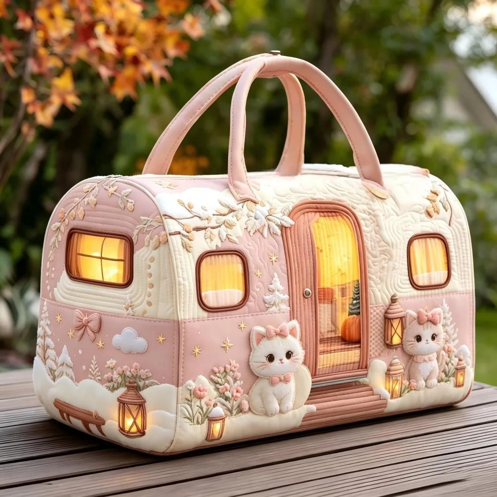 Christmas Quilted Travel Tote Bag – Vintage Camping Car Handbag A decorative pink and cream camper trailer handbag with raised cat and winter scene details, shown outdoors on a wooden surface with blurred foliage in the background.
