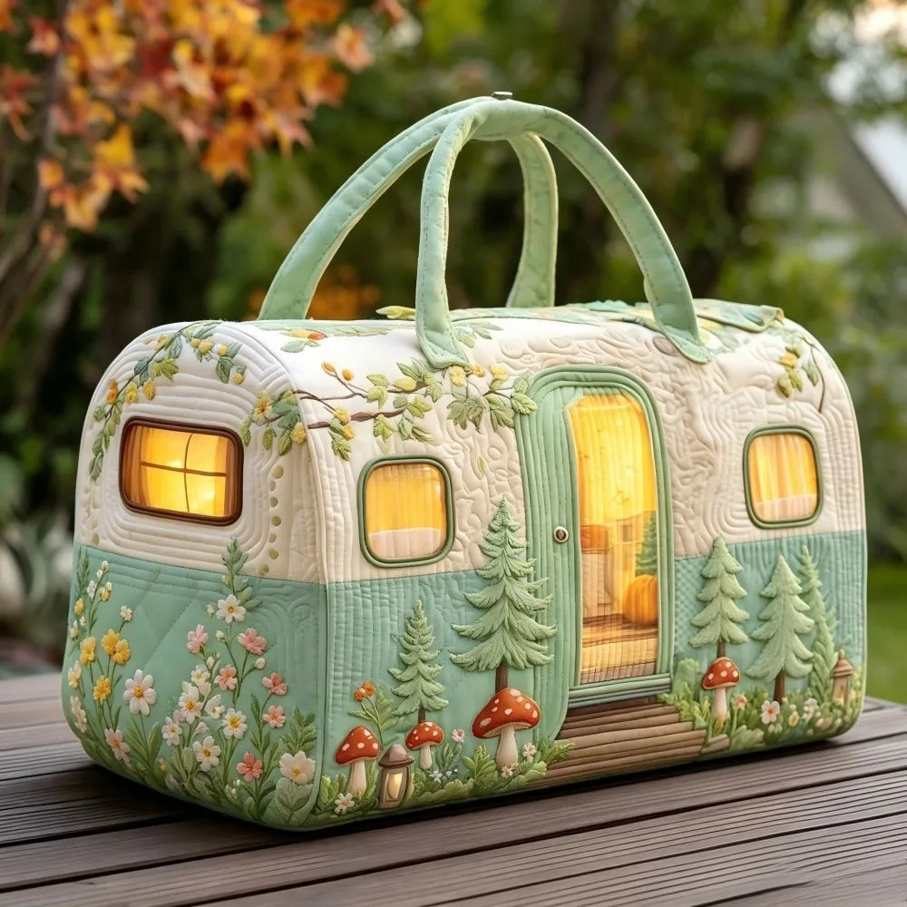 Christmas Quilted Travel Tote Bag – Vintage Camping Car Handbag A decorative camping-themed handbag shaped like a vintage trailer, with a light green and cream body, floral and tree patterns, glowing warm window lights, and two top handles, photographed outdoors on a wooden surface with blurred foliage in the background.