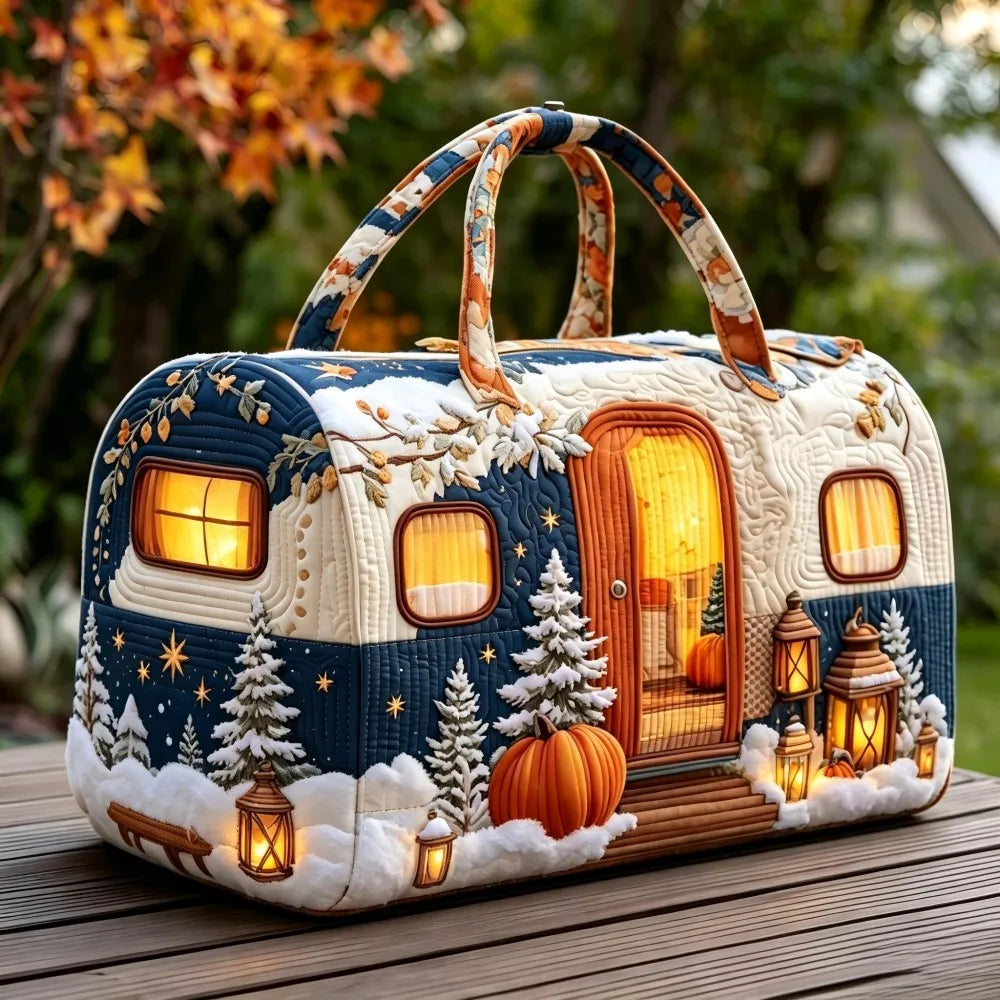 Christmas Quilted Travel Tote Bag – Vintage Camping Car Handbag A decorative handbag shaped like a winter camper trailer, placed on a wooden table outdoors. The bag has a quilted texture, a dark blue and cream body, faux snow, evergreen trees, glowing lanterns, and warm lights inside, with patterned handles.