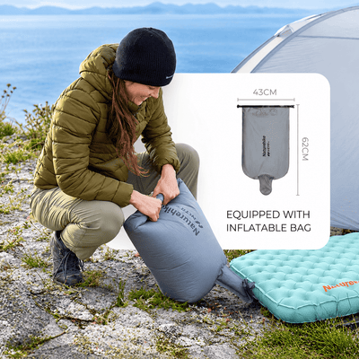 A woman in outdoor gear crouches beside a tent and ocean, handling a gray Nautica inflatable sleeping bag. An inset diagram shows the bag dimensions (43cm x 26cm), and a turquoise sleeping pad is visible on the ground.