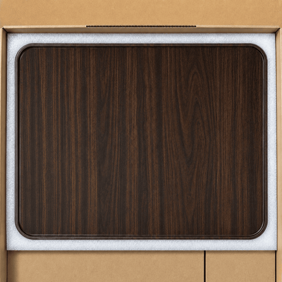 A dark brown wood grain rectangular tray with rounded corners, shown inside its light gray protective foam packaging insert against a tan cardboard background.