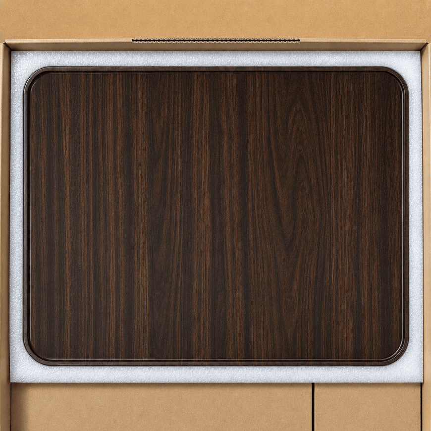 A dark brown wood grain rectangular tray with rounded corners, shown inside its light gray protective foam packaging insert against a tan cardboard background.