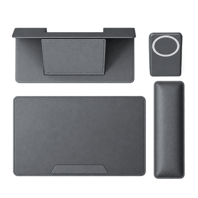 A dark gray multi-piece ergonomic desk pad set on a solid white background, including a desk mat with an integrated stand, a matching wrist rest, a rectangular mouse pad, and a small square pad with a circular cutout.