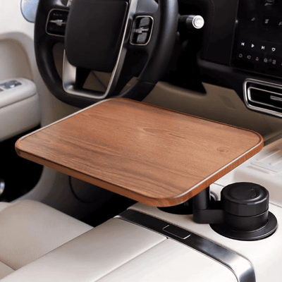 A wooden car desk tray mounted on a center console cup holder inside a vehicle, shown with the steering wheel and dashboard in view.
