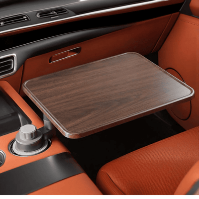 A fold-out car console tray table with a dark brown wood-grain finish, shown extended over an orange leather car interior.