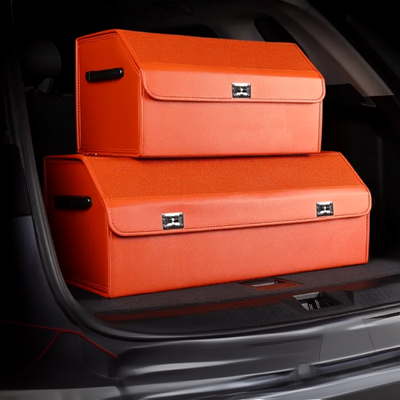 Two bright orange car trunk organizer boxes stacked inside a dark car trunk.