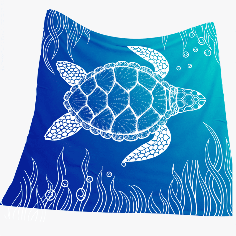 A square textile, likely a beach towel or scarf, featuring a white line-art illustration of a sea turtle swimming on a blue gradient background with white seaweed and bubble designs.