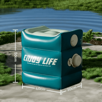 An inflatable camping shower box in teal green with white text reading 'ENJOY LIFE' and dimension lines showing 50cm height, 40cm width, and 30cm depth, set outdoors near water with grass and pavement visible.