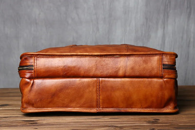 Brown leather suitcase on a wooden surface with a gray background