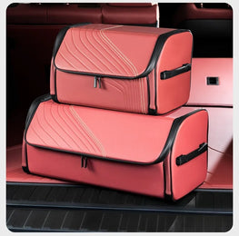 Two coral pink car trunk organizer bags with black trim stacked inside a car trunk.