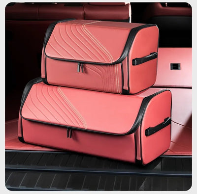 Two coral pink car trunk organizer bags with black trim stacked inside a car trunk.