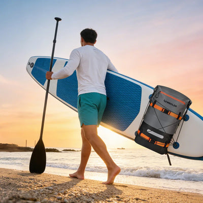 Man carrying a stand-up paddleboard and backpack on a beach at sunset