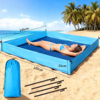 A blue inflatable beach sun pad with a woman lying on it, shown on a sandy beach with ocean and palm trees in the background. Black tent stakes and a blue drawstring storage bag are displayed in the foreground, with dimension labels 145cm, 185cm, and 25cm overlaid on the image.