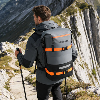 Person hiking on a mountain path with a gray and orange backpack labeled 'Newboler'.
