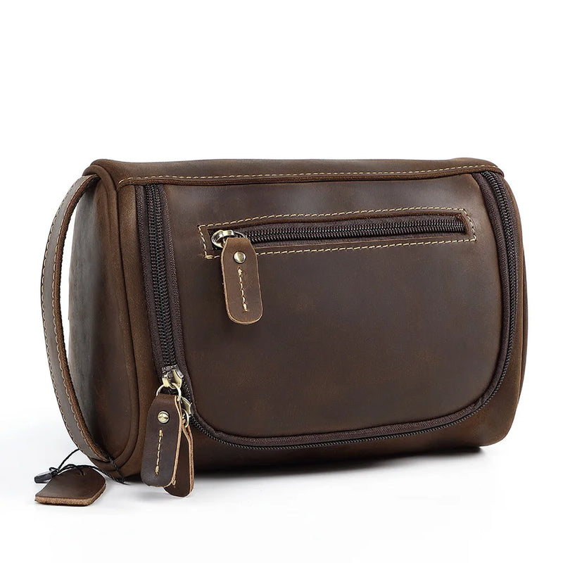A brown faux-leather toiletry bag shown open, revealing its interior compartments, mesh pockets, and storage space filled with travel items, on a white background.