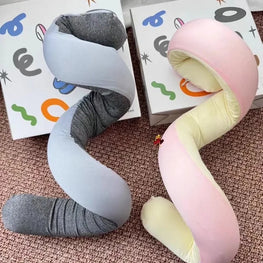 Two coiled neck pillows, one gray and one pink, on a textured surface with colorful abstract designs in the background.