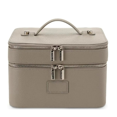 A structured rectangular makeup case in textured taupe leather with a top handle, two zip compartments, and silver-tone hardware, shown on a plain white background.