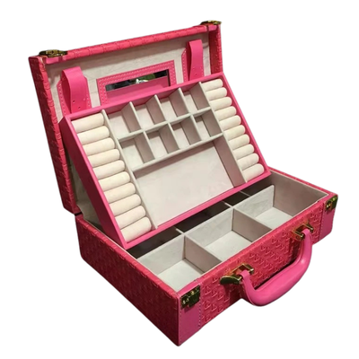 A pink textured hard case organizer shown open, with a bright pink handle, gold-tone hardware, and multiple interior compartments including ring rolls, a mirror, and divided sections.