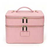 A pink faux-leather makeup case with a top handle, double zipper compartments, and gold-tone hardware, shown against a plain white background.