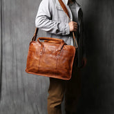 Person holding a brown leather briefcase against a gray background