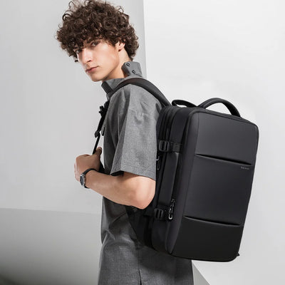 Person wearing a black backpack against a plain background