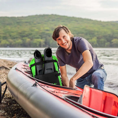 Man preparing a kayak on a lakeside with green hills in the background