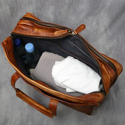 Brown leather bag with items including bottles and cloths on a gray background
