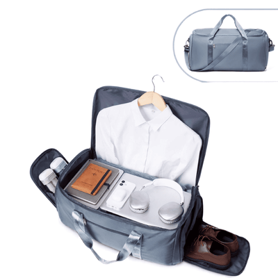 A gray travel bag shown open, filled with a white shirt, notebook, phone, headphones, toiletries, and brown shoes. A smaller inset at the top right shows the closed bag with handles and strap on a white background.