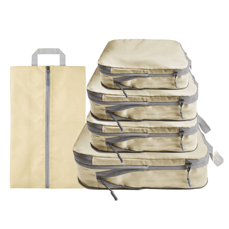 A set of beige packing cubes and a matching zippered sleeve with gray zippers and handles, shown on a plain white background.