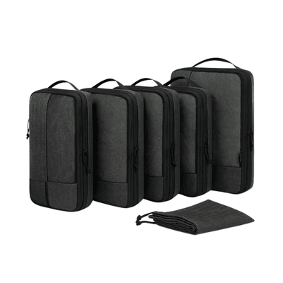 Five dark gray packing cubes of different sizes arranged in a row, with a matching dark gray drawstring pouch placed in front, on a plain white background.